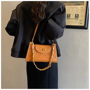 Detail of vintage brown textured leather underarm bag with gold chain and metal lock