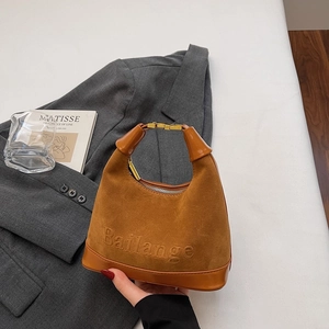 Vue détaillée du sac en daim marron caramel avec poignées en cuir et finitions métalliques