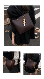 Détail du sac cabas tissé marron foncé avec un pompon bohème en perles de bois