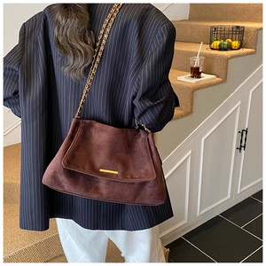 Détail du sac fourre-tout en daim marron foncé avec boucle dorée et bandoulière en chaîne