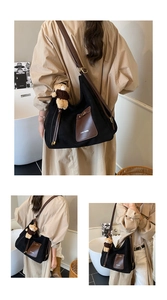 Detail view of large black canvas hobo bag with brown leather pocket and plush bear charm