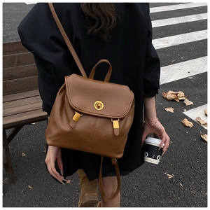 Détail d'un sac à dos en cuir marron avec boucle dorée et fermeture à fermoir rotatif
