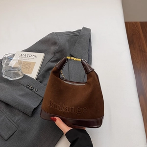 Détail du sac dumpling marron foncé en daim avec coutures en cuir lisse et boucles dorées