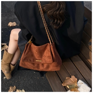 Photo en extérieur d'un sac cabas marron en daim avec chaîne sur un banc pour l'automne