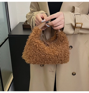 Gros plan d'un sac hobo en peluche marron avec poignée lisse tenu par un mannequin élégant