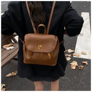Détail d'un sac à dos vintage en cuir marron avec fermoir doré sur fond d'automne