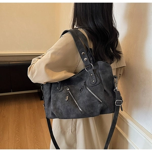 Vue détaillée d'un grand sac cabas rétro gris foncé avec zips porté par un mannequin