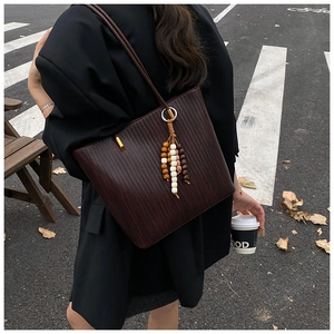 Détail du sac cabas marron foncé tissé avec pompons en perles et anneau en métal