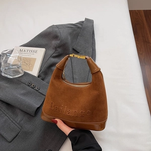 Gros plan détaillé du sac en daim marron avec garniture en cuir et boucle dorée