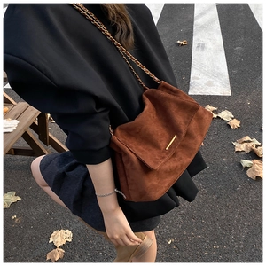 Détail du sac cabas en daim caramel avec barre dorée et bandoulière en chaîne élégante
