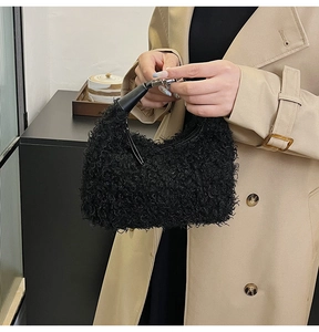 Détail d'un sac noir en laine bouclée avec boucle en métal argenté et anse en cuir