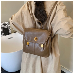 Détail d'un sac à dos vintage marron avec fermoir tournant en métal doré et rabat pliable