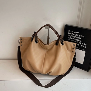 Dettaglio della grande borsa tote in tela kaki con manici in pelle marrone e finitura testurizzata