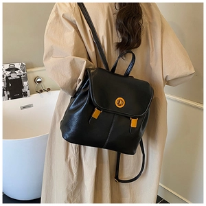 Détail d'un sac à dos en cuir noir avec fermoir tournant doré et fines bretelles en cuir