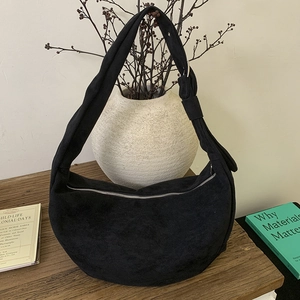 Detail of black suede hobo bag featuring a silver metal zipper and adjustable side buckle