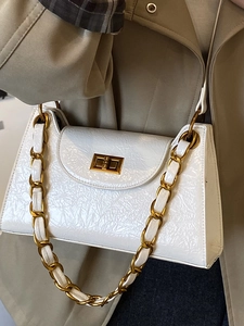 French vintage white shoulder bag with gold chain strap and square twist lock on beige coat