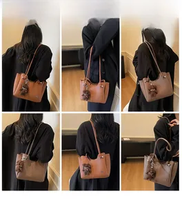 Détail du sac fourre-tout marron texturé avec logo métallique et pendentif ourson