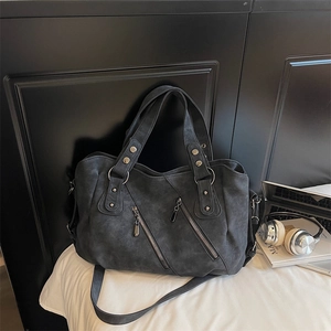 Détail d'un sac cabas gris foncé mat avec fermetures éclair décoratives et clous argentés