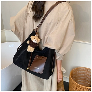 Detail of black large capacity shoulder bag with brown pocket and cute bear charm