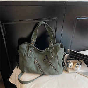 Détail du grand sac cabas vert foncé montrant la texture, les zips et les anneaux argentés