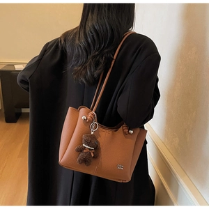 Gros plan sur un sac cabas en cuir marron texturé avec pendentif ours en peluche