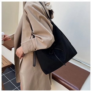 Vue détaillée du grand sac cabas noir avec nœud coulissant porté par un mannequin en extérieur