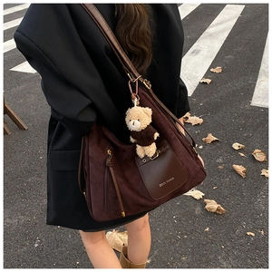 Detailed view of deep brown suede crossbody bag with a cute plush bear charm accessory