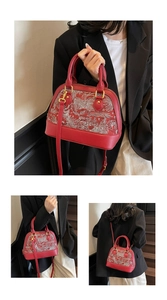 Detail of red shell-shaped handbag with intricate floral embroidery and gold hardware