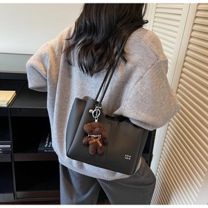 Détail du cabas en cuir grainé noir avec un petit pendentif en forme d'ours