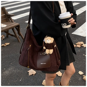 Close-up of a large brown faux suede tote bag featuring a cute plush bear charm detail