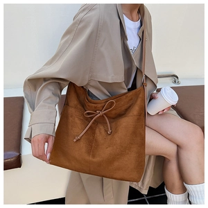 Détail d'un sac cabas en daim marron avec cordon de serrage et coutures visibles