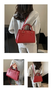 Dettaglio borsa rossa con goffratura coccodrillo che mostra logo dorato e trama elegante