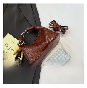 Detail of dark brown woven leather bag with wooden bead charm and metal buckle