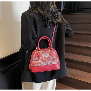 Detail of red leather shell bag with floral embroidery and gold hardware on model