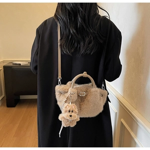 Close-up of soft plush bucket bag with leather handles and cute teddy bear pendant charm