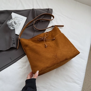 Détail du sac cabas en daim caramel avec nœud de serrage et bandoulière pour l'automne