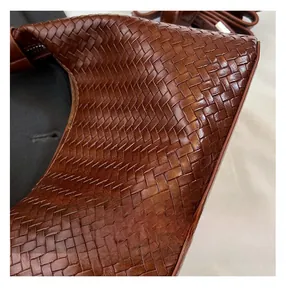 Macro detail of brown woven leather texture showing high-quality crossbody bag craftsmanship