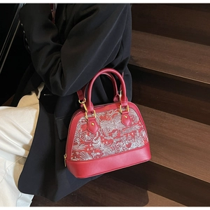 Detail view of red shell bag with intricate embroidery pattern and gold metal hardware