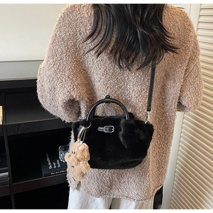 Detail of black faux fur bucket bag with plush bear charm and adjustable strap
