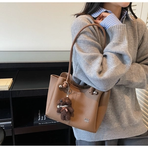 Détail du sac fourre-tout en cuir marron avec breloque d'ours en peluche mignonne