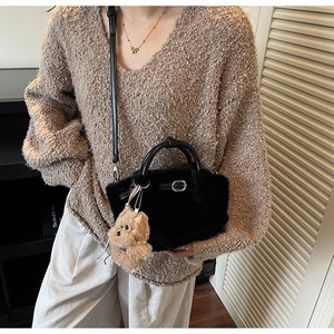 Crossbody plush bucket bag in black featuring a faux fur texture and brown bear charm