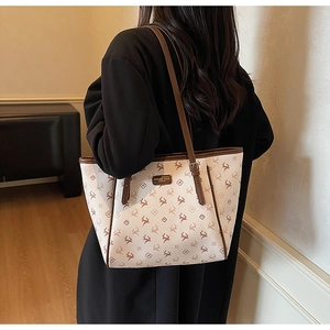 Détail du sac fourre-tout crème avec motif monogramme cerf, cuir brun et logo métallique