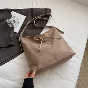 Vue détaillée du cabas en daim marron avec nœud décoratif et bandoulière réglable