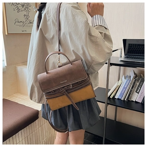 Detail view of retro two-tone crossbody bag in brown and yellow with top handle