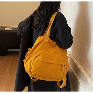 Detailed side view of yellow nylon tote bag with side pocket and spacious zip compartment
