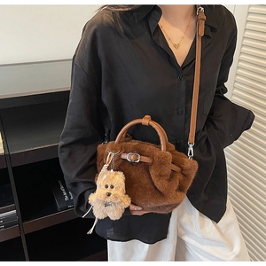 Detail of dark brown plush bucket bag featuring a soft teddy bear charm and gold buckle strap