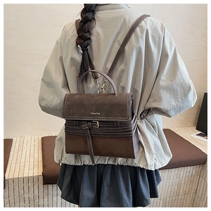 Detail of vintage brown shoulder bag showing white stitching and metal buckle accents
