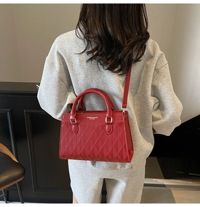 Dettaglio della borsa trapuntata in pelle rossa con logo dorato portata da una modella