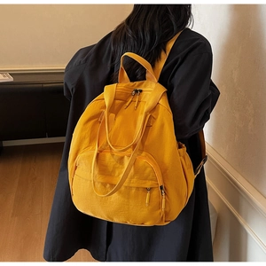 Rear view of a model wearing a vibrant yellow nylon backpack with sleek zippers