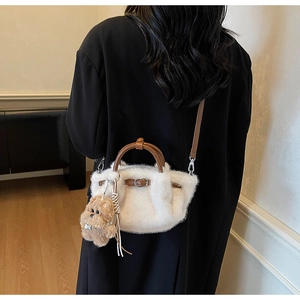 Detail of white faux fur bucket bag with brown leather handles and a cute dog charm